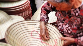 Frau beim Nähen eines Hutes in Vietnam